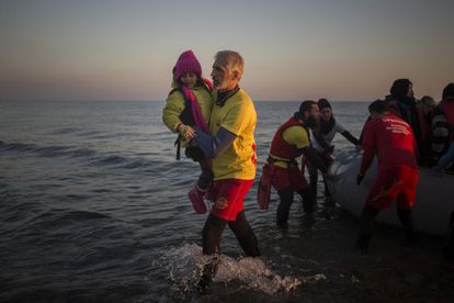 Enrique Álvarez ayuda a bajar a una niña refugiada en una playa cercana a la ciudad de Mytilene, en la isla de Lesbos (Grecia), en 2015.